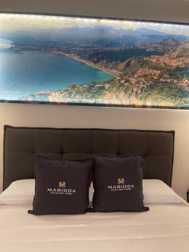 a painting above a bed with a view of the ocean at MARIDDA-experience rooms- in Giardini Naxos