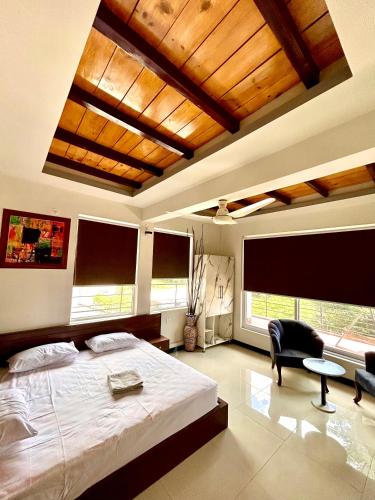 a bedroom with a bed and a chair and windows at Republika Central Hotel & Resort in Abbottābād