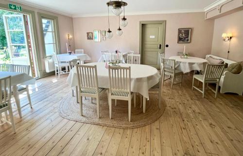 uma sala de jantar com mesas e cadeiras brancas em Lydde Gård em Kinna