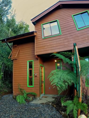 a wooden house with green windows and aafia at La Rueda del Chucao in Valdivia