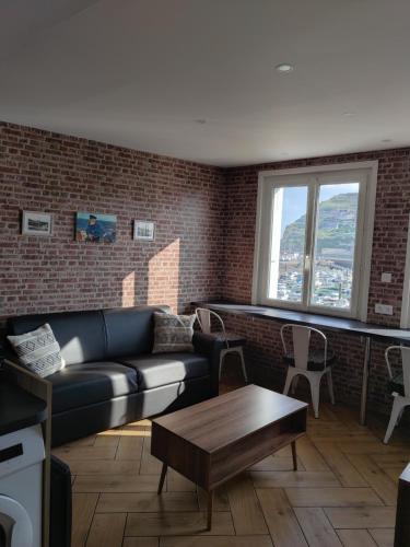 a living room with a couch and a brick wall at La rose des vents in Fécamp