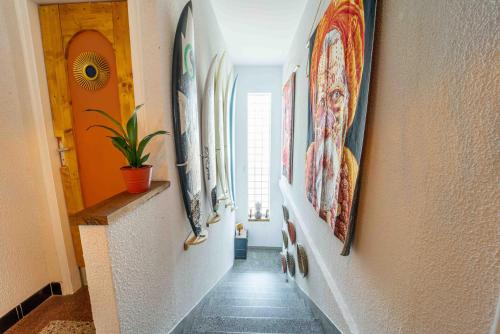 a hallway with paintings on the walls of a house at La Boga L'Auberge à l'ambiance Surf à Biscarrosse Plage in Biscarrosse-Plage