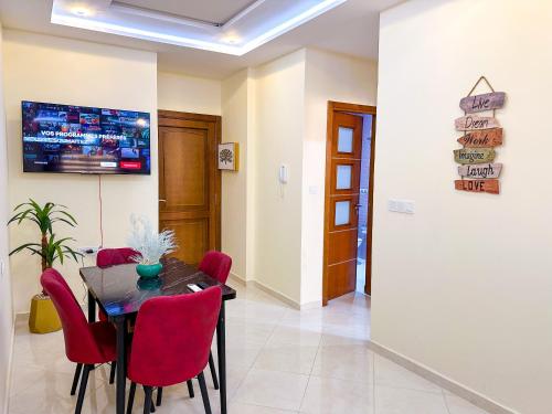 a dining room with a table and red chairs at Elite Holiday Home - Luxury & Centric Flat in Tangier