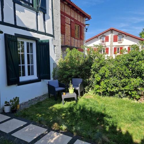 une maison avec une chaise et un banc dans la cour dans l'établissement Charmant appartement avec jardin, à Larressore