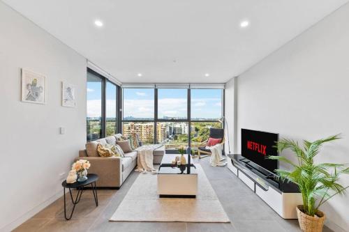 a living room with a couch and a tv at City views & New 3b2b1p Apt in Homebush in Sydney