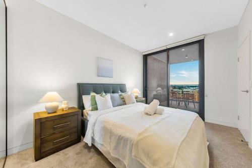 a bedroom with a large bed and a large window at City views & New 3b2b1p Apt in Homebush in Sydney