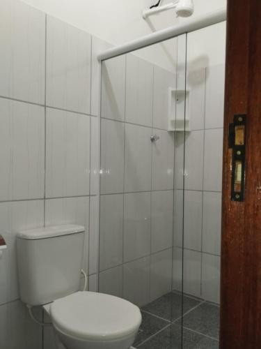 a bathroom with a toilet and a glass shower at Pousada Baía do Sol Saquarema in Saquarema