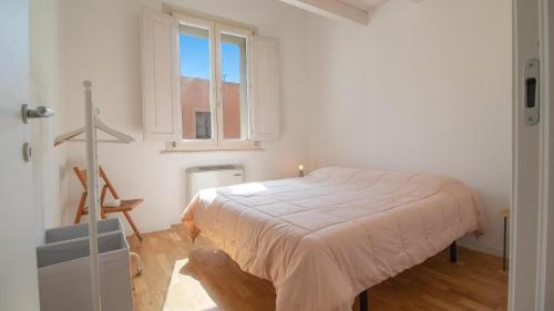 a white bedroom with a bed and a window at Corte Coronardi - Elegante casa Campidanese in Quartu SantʼElena