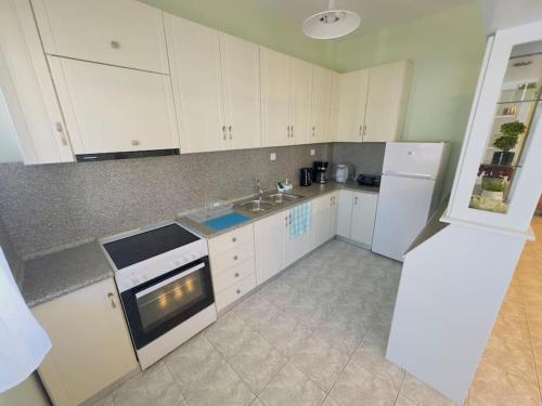 a kitchen with white cabinets and a sink and a refrigerator at oLive Home in Alexandroupoli