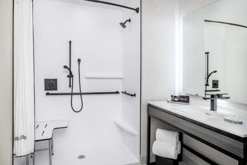 a white bathroom with a sink and a shower at The Artisan at Tuscan Village, Salem, NH, a Tribute Portfolio Hotel in Salem