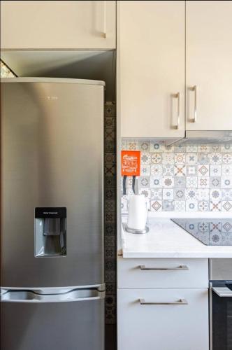 a stainless steel refrigerator in a kitchen with white cabinets at Casa Peixinha in Aveiro