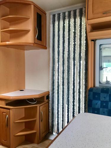 a small kitchen in a caravan with a window at Komfort-Caravan mit Vorzelt in Loitz
