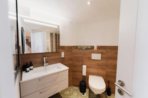 Un baño con inodoro, lavabo y espejo. en Modernes Tiny House mit Sonnenterrasse, en Ediger-Eller