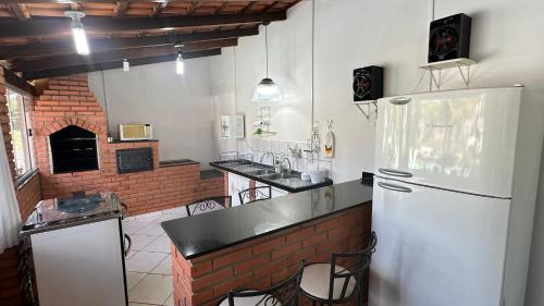 a kitchen with a white refrigerator and a brick oven at Casa Sossego com Piscina em Chapada dos Guimarães in Chapada dos Guimarães