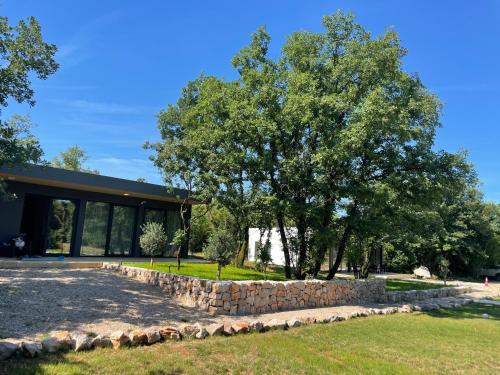 a building with a stone wall and a tree at KOKO VILLAGE in Podgorica