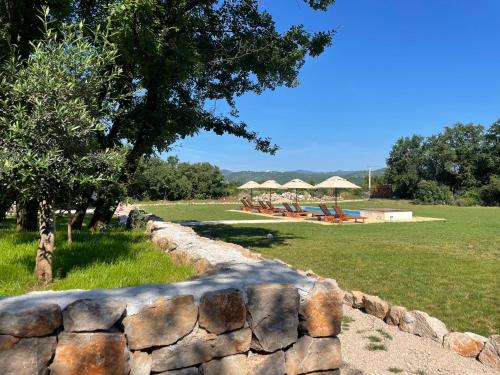 a stone wall next to a field with a pool at KOKO VILLAGE in Podgorica