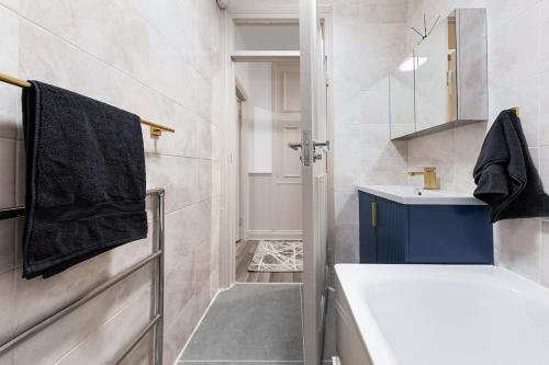 a bathroom with a white sink and a blue towel at Brand New 3 Bedroom flat in Central London in London