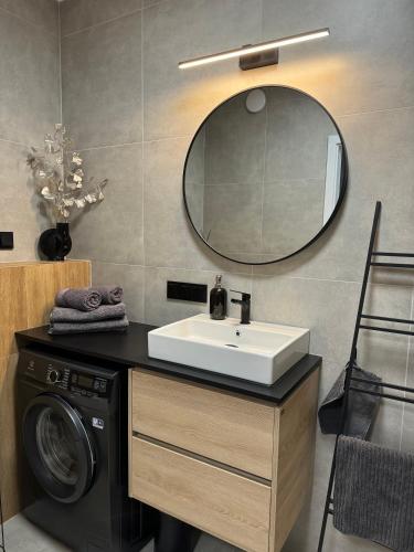 a bathroom with a sink and a washing machine at Red bridge Resort - Apartament & SPA in Dziwnów
