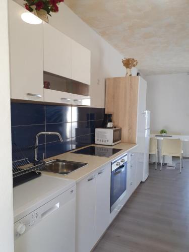 a white kitchen with a sink and a microwave at 6 M, 50 m do plaže in Barbat na Rabu