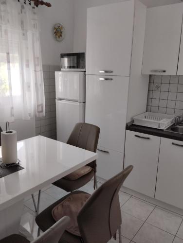 a white kitchen with a white table and chairs at 6 M, 50 m do plaže in Barbat na Rabu