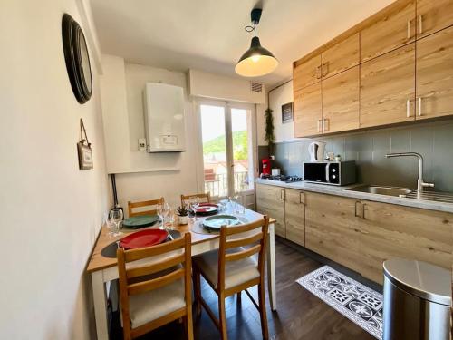 une cuisine avec une table et des chaises dans une cuisine dans l'établissement Epicea, bel appartement avec balcon au centre ville, à Gérardmer