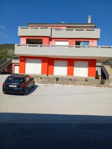 a car parked in front of a red and white building at Apartments with parking space Hreljin, Kraljevica - 22478 in Hreljin