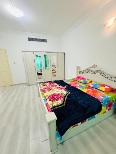 a bedroom with a bed with a colorful blanket on it at Feel like a home away home in Ajman