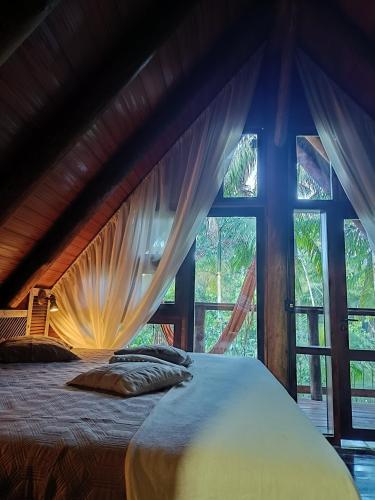 a bed in a room with a large window at Chalé Graciosa in Rodeio
