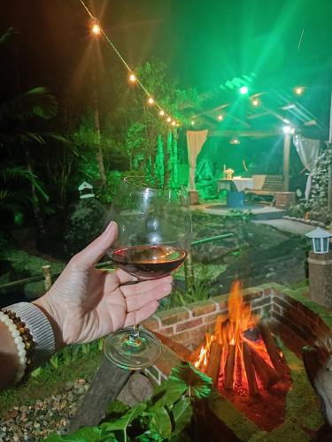 a person holding a glass of wine in front of a fire at Chalé Graciosa in Rodeio