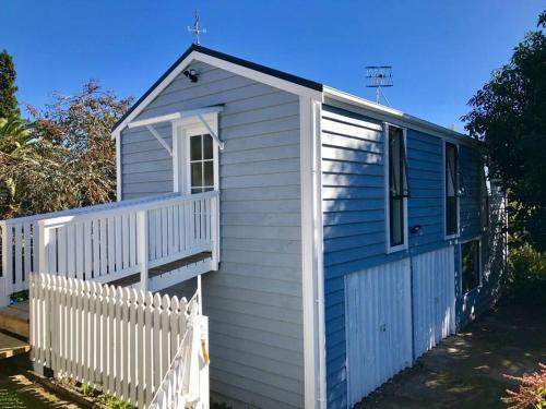 a small blue building with a white fence at Historic Barn Loft - Private & Spacious in Tauranga