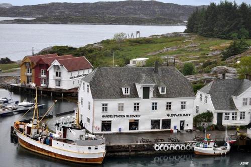 a boat is docked next to a large white building at Not Taking Guests in Eide