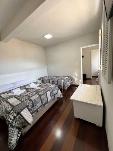 a bedroom with two beds and a table in it at Estadia das Gerais - Suíte Privativa 5 in Ouro Preto