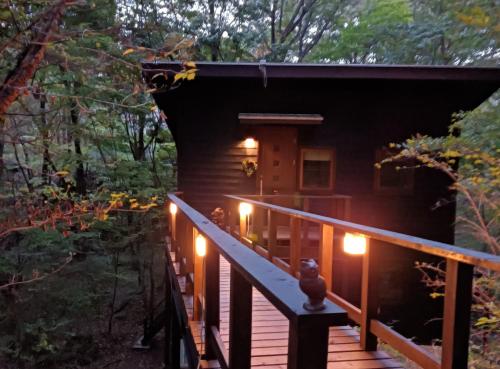 a cabin in the woods with lights on the deck at Nasu Country Cottage in Nasu-yumoto