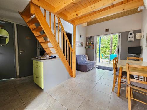 une cuisine et une salle à manger avec un escalier en bois dans l'établissement Charmante Maison avec Cour Privative - Proche Plage et Commerces, Animaux Acceptés sur Demande - FR-1-476-212, à La Tranche-sur-Mer
