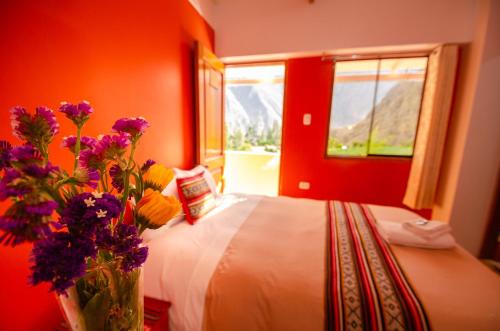 a bedroom with a bed with a vase of flowers at Peru Quechua's Lodge Ollantaytambo in Ollantaytambo