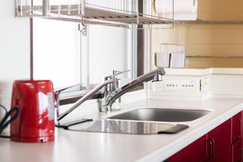 a kitchen counter with a sink and a red appliance at Gardenia in Aji