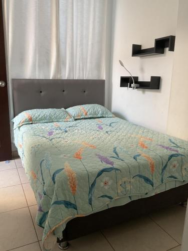 una camera da letto con un letto con un piumone e un cuscino di Apartamento familiar amoblado a Pimentel