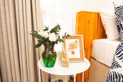 a vase with flowers on a table next to a bed at Bruma Homes in Ponta do Ouro
