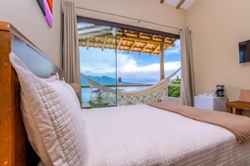 Un dormitorio con una cama y una ventana grande. en Suite Canto do Embauba, en Ilhabela