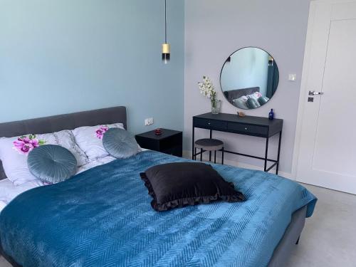 a bedroom with a blue bed and a mirror at PaVoni Terazze Verdi Łeba in Łeba