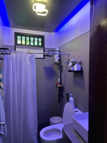 a bathroom with a white toilet and a sink at The Downtown Cabin Bohol in Tagbilaran City