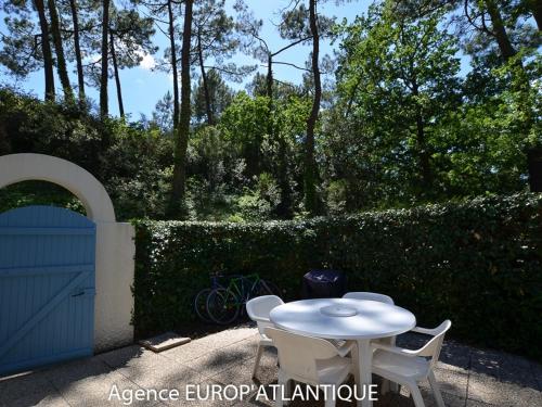 une table et des chaises blanches à côté d'une clôture dans l'établissement Maison T3 bis La Palmyre - Terrasse, Wifi, Parking, Proche Mer et Commerces - FR-1-705-80, aux Mathes