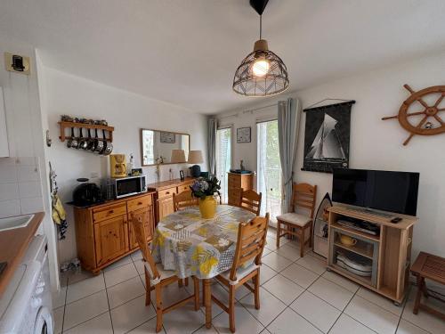 une cuisine avec une table et des chaises et une télévision dans l'établissement Appartement lumineux au port de plaisance des Sables-d'Olonne avec balcon et équipements modernes - FR-1-197-602, à Les Sables-dʼOlonne