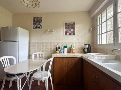 Il comprend une cuisine équipée d'un réfrigérateur blanc, d'une table et de chaises. dans l'établissement Villa avec Grande Piscine, 6 Chambres, Tennis, Plage Privée - La Palmyre - FR-1-705-83, aux Mathes