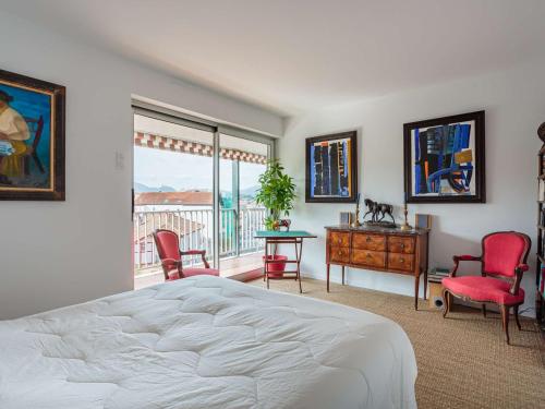 - une chambre avec un lit, des chaises et un balcon dans l'établissement Appartement moderne en centre-ville avec balcon et parking à 400m de la plage - FR-1-4-693, à Saint-Jean-de-Luz
