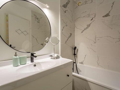une salle de bain avec un lavabo, un miroir et une baignoire dans l'établissement Appartement moderne en centre-ville avec balcon et parking à 400m de la plage - FR-1-4-693, à Saint-Jean-de-Luz