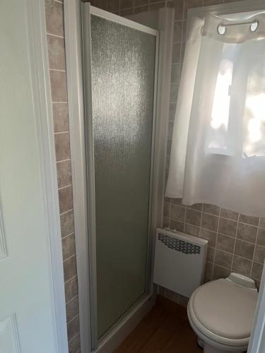 La salle de bains est pourvue de toilettes et d'une porte de douche en verre. dans l'établissement Chez Mayan et Doly 206 rue des Sapins, à Clarke City