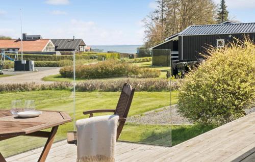 a wooden table and chair on a deck with a view of a yard at Gorgeous Home In Juelsminde With Wifi in Sønderby
