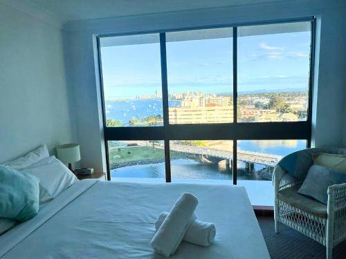 a bedroom with a white bed with a large window at Broadwater Shores Waterfront Apartments in Gold Coast