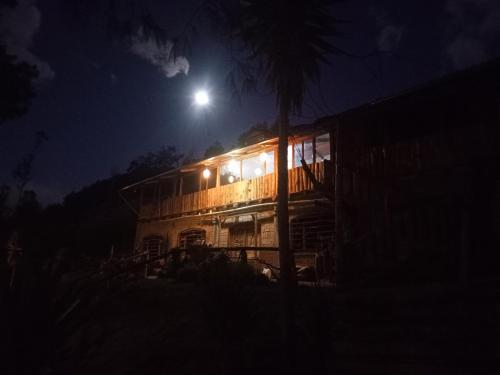 Una casa de noche con la luna detrás. en EL TRAPICHE, en Sigchos